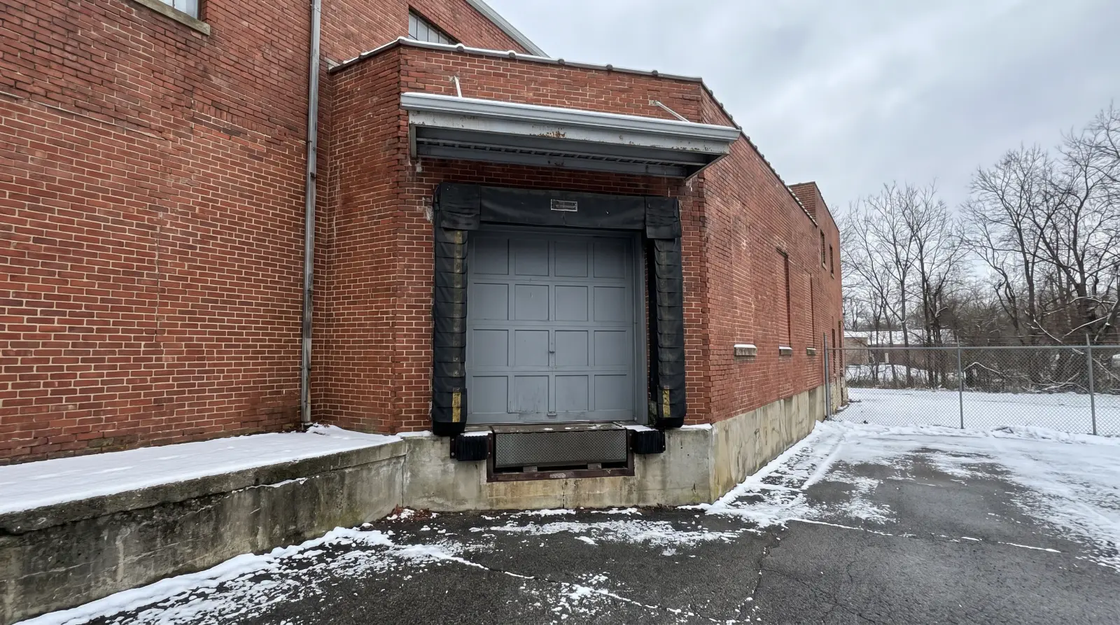 Sectional overhead door on a brick building loading dock with a foam dock seal and light snow