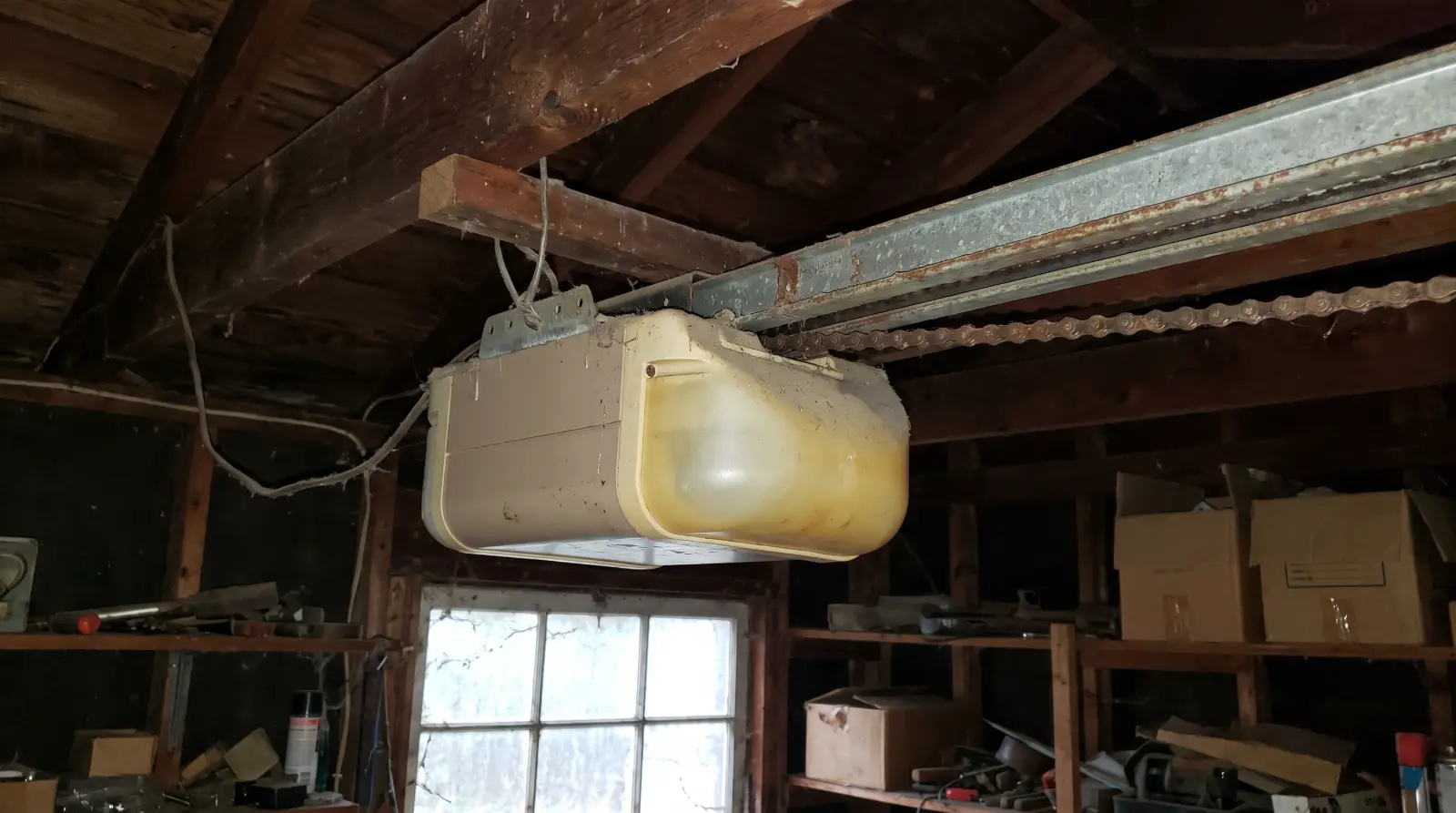 Old worn chain-drive garage door opener on the ceiling of an older garage